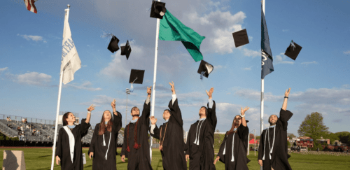 seven graduates throwing their caps after graduating